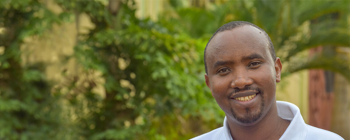 Donatian Ndagijima smiles in front of green trees