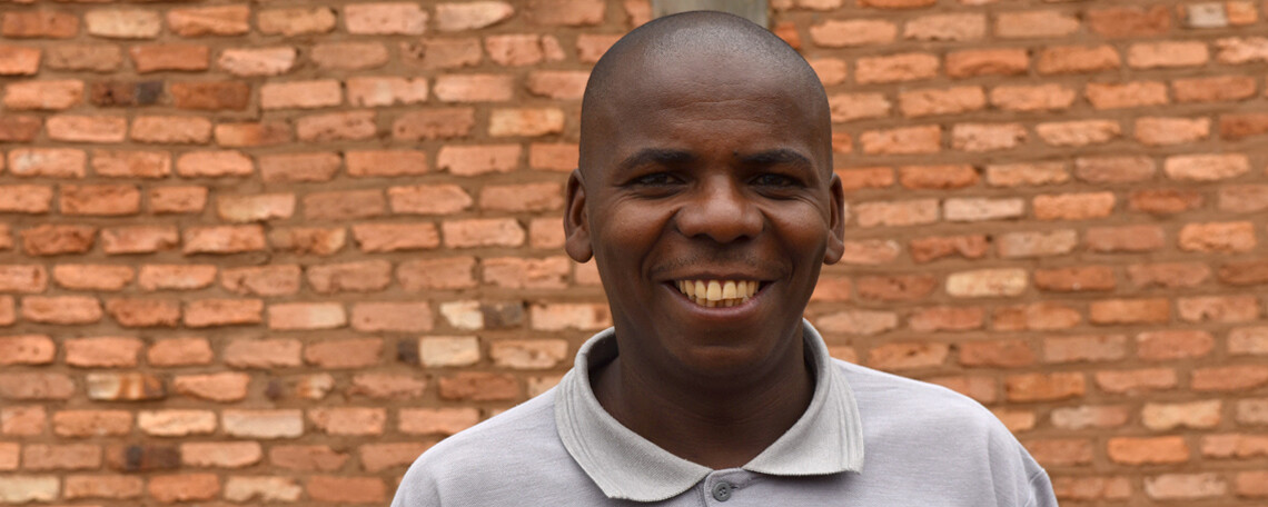 Isaiah smiles outside a brick building