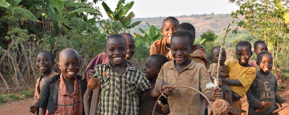 a group of Children pose and smile for the camera in the evening light, one holds a hoop