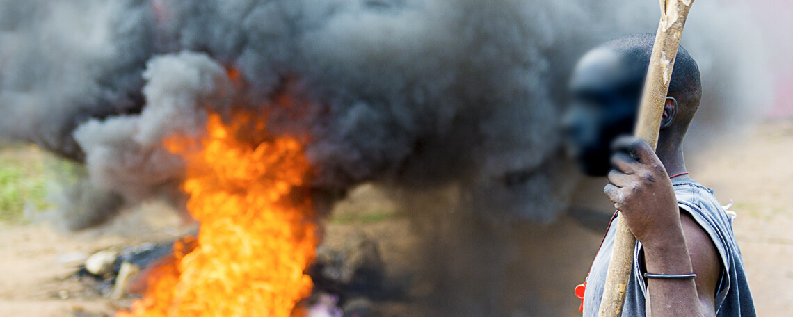 a man with a staff stands next to a fire in the street