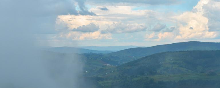peaceful green Burundi hills with clouds and fog as the sun shines through